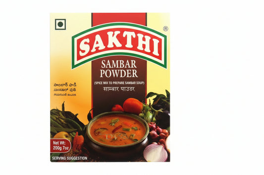 Box of Sakthi Sambar Powder with a bowl of soup and vegetables on a white background